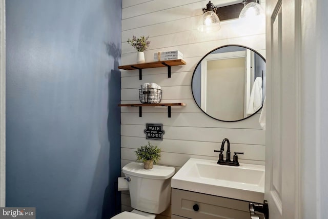 bathroom with wooden walls, toilet, and vanity