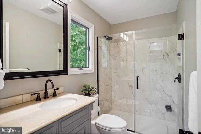 bathroom with a marble finish shower, vanity, toilet, and visible vents