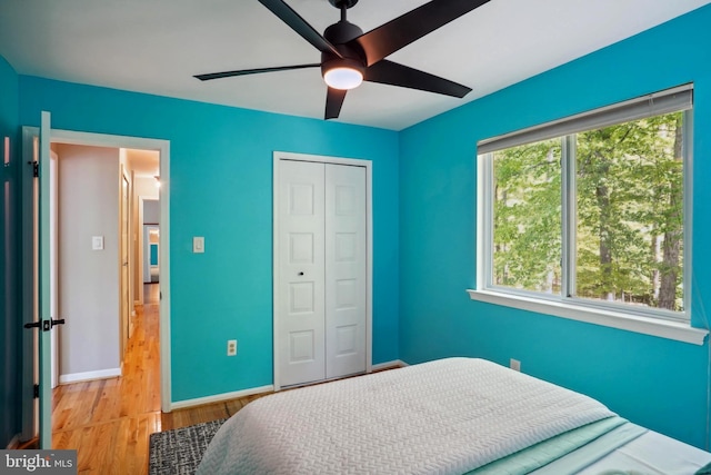 bedroom with a closet, a ceiling fan, baseboards, and wood finished floors