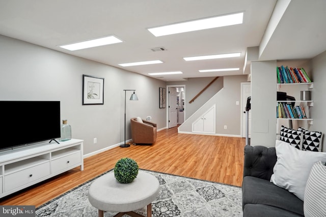 living room featuring visible vents, baseboards, stairs, and wood finished floors