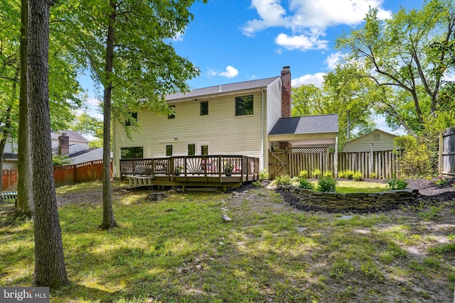 rear view of property with a fenced backyard, a wooden deck, a chimney, and a lawn