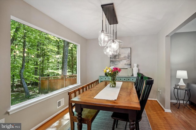 dining area featuring a chandelier, baseboards, visible vents, and wood finished floors