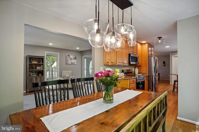 dining space featuring an inviting chandelier, baseboards, recessed lighting, and light wood-style flooring