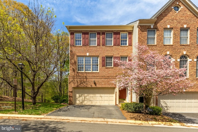 multi unit property featuring driveway, brick siding, and a garage