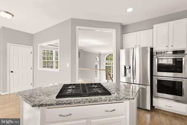 kitchen with light stone counters, white cabinetry, light wood finished floors, and stainless steel appliances
