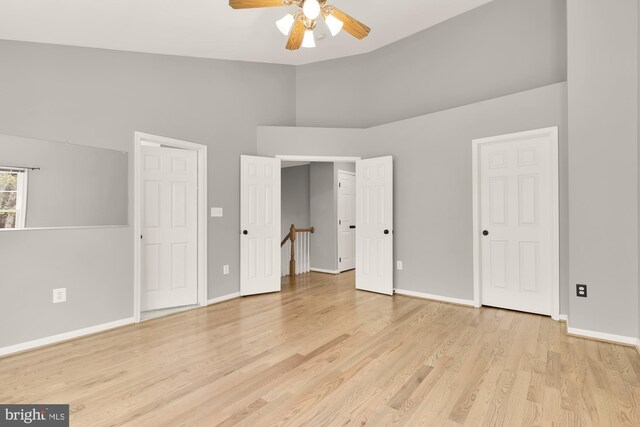 unfurnished bedroom featuring high vaulted ceiling, baseboards, and light wood-style floors