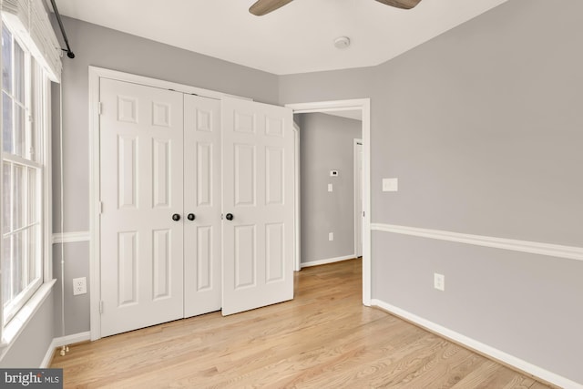 unfurnished bedroom featuring light wood-style floors, a closet, a ceiling fan, and baseboards