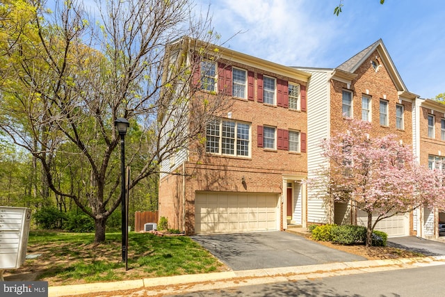 townhome / multi-family property with brick siding, an attached garage, and aphalt driveway