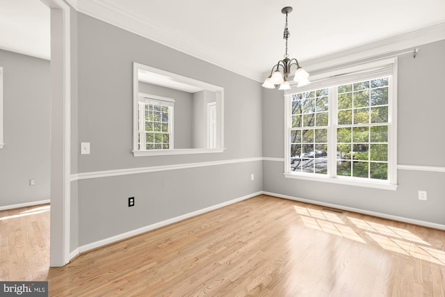 unfurnished dining area with visible vents, baseboards, an inviting chandelier, wood finished floors, and ornamental molding