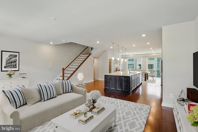 living area featuring recessed lighting, dark wood-type flooring, baseboards, and stairs