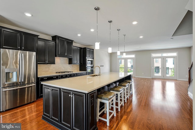 kitchen featuring dark cabinetry, a large island with sink, french doors, and appliances with stainless steel finishes
