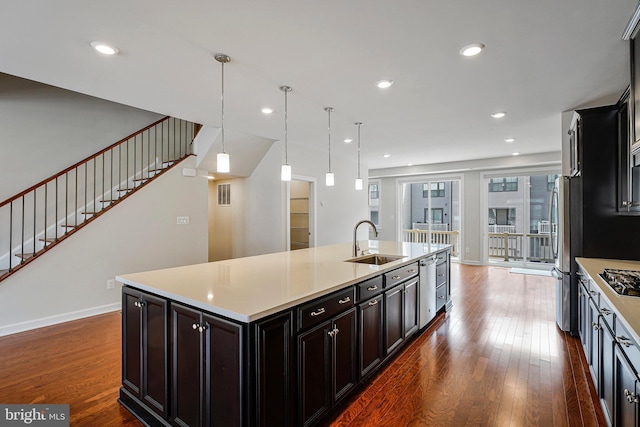 kitchen featuring light countertops, stainless steel appliances, dark wood finished floors, and a sink