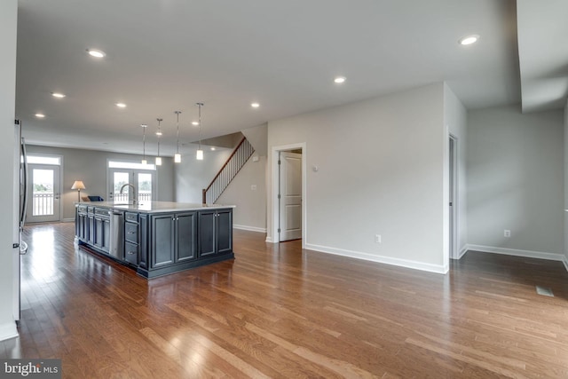 kitchen with a sink, baseboards, a kitchen island with sink, and wood finished floors