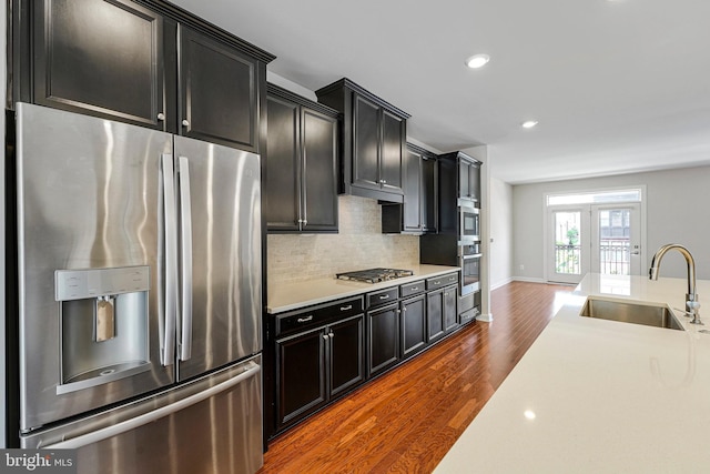 kitchen featuring stainless steel appliances, dark cabinetry, dark wood-style floors, and a sink