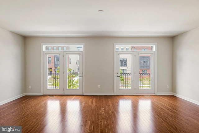 empty room featuring a wealth of natural light, baseboards, and wood finished floors