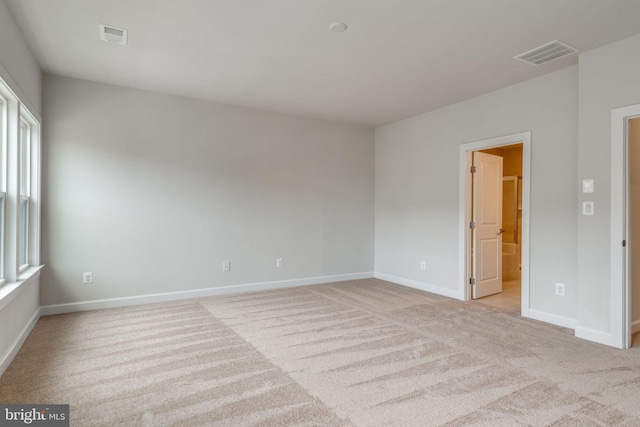 spare room featuring visible vents, baseboards, and light carpet