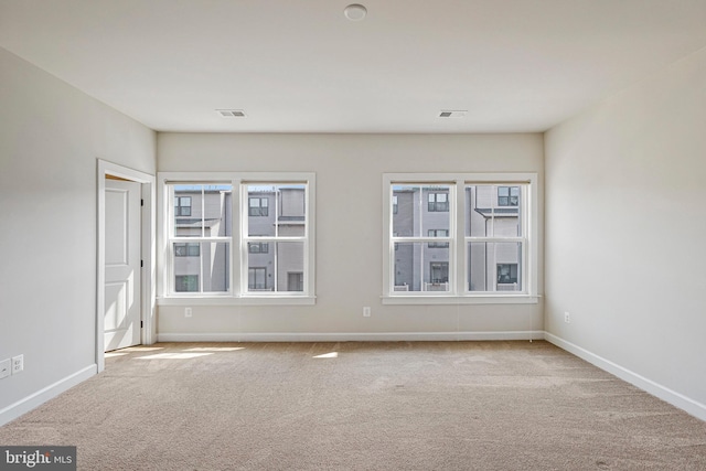 empty room with carpet floors, baseboards, and visible vents