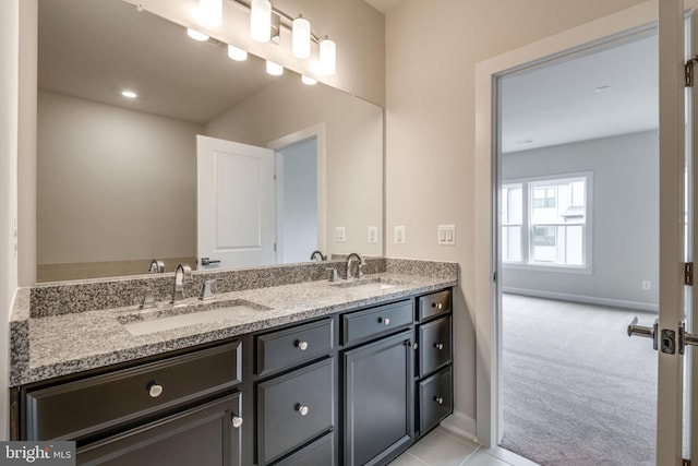 bathroom with double vanity, baseboards, and a sink