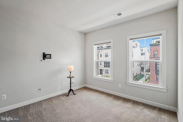 carpeted spare room featuring visible vents and baseboards