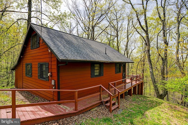 exterior space featuring a deck and a shingled roof