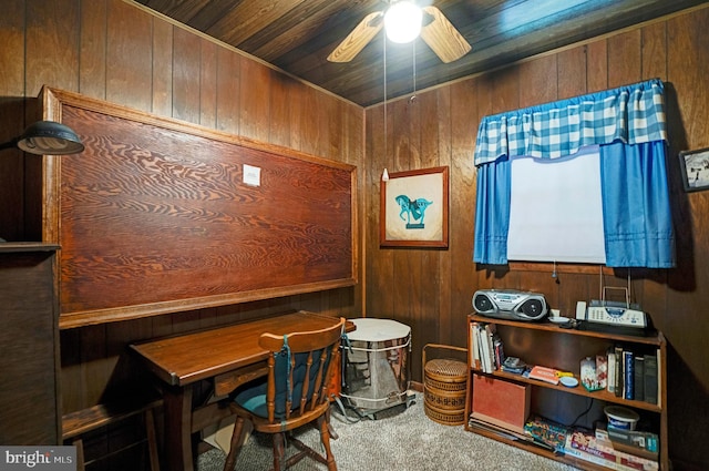 carpeted office space featuring wooden walls, wooden ceiling, and a ceiling fan