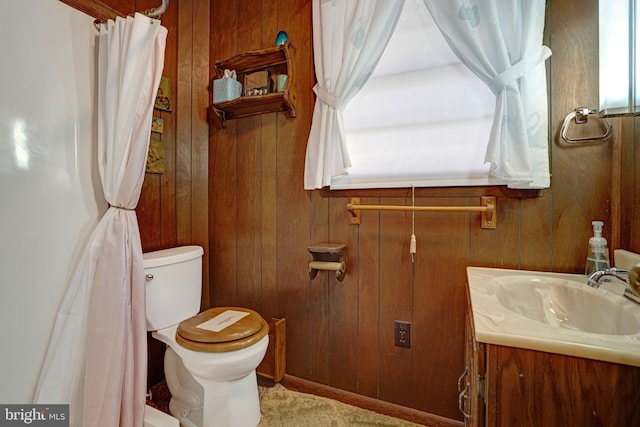 bathroom with wooden walls, toilet, and vanity