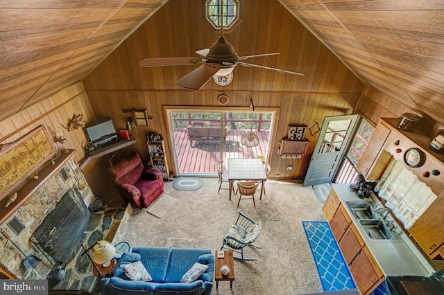 carpeted living area featuring wooden walls, vaulted ceiling, wooden ceiling, and a healthy amount of sunlight