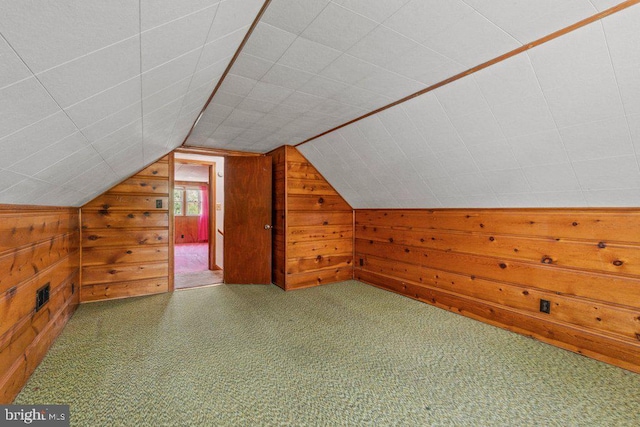 bonus room with carpet flooring, visible vents, wood walls, and vaulted ceiling