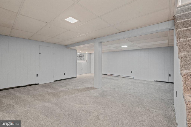 finished basement featuring carpet floors, a baseboard radiator, and a paneled ceiling