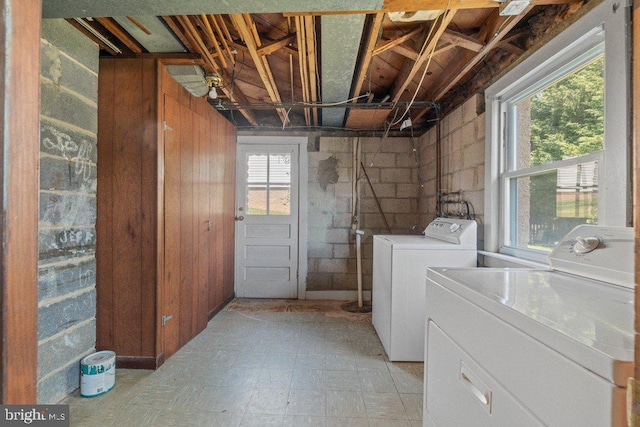 laundry area featuring concrete block wall, light floors, laundry area, and washing machine and clothes dryer