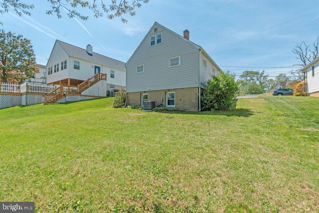 back of property with stairs, central AC, a yard, and a chimney