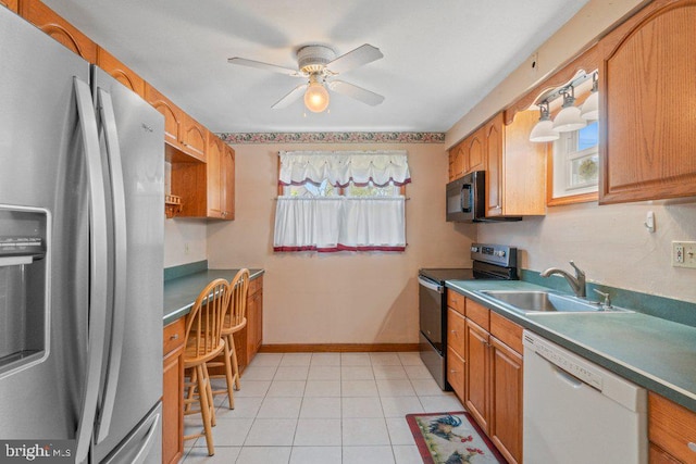 kitchen featuring a ceiling fan, appliances with stainless steel finishes, brown cabinets, a sink, and light tile patterned floors