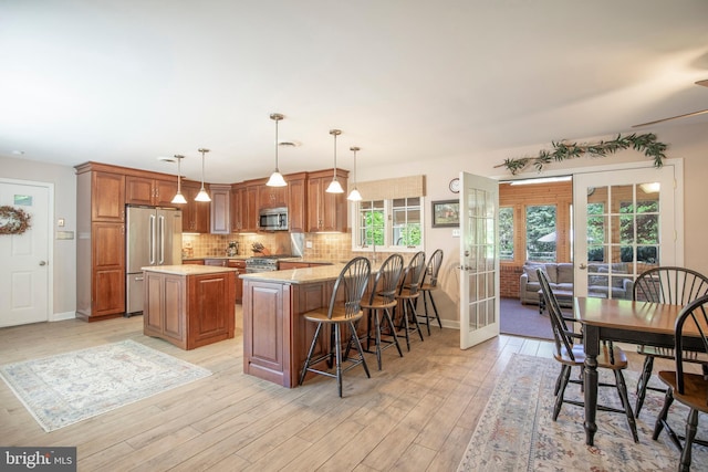 1701 Holicong Rd, New Hope, PA 18938 - kitchen featuring brown cabinets, light wood-style flooring, stainless steel appliances, a peninsula, and tasteful backsplash