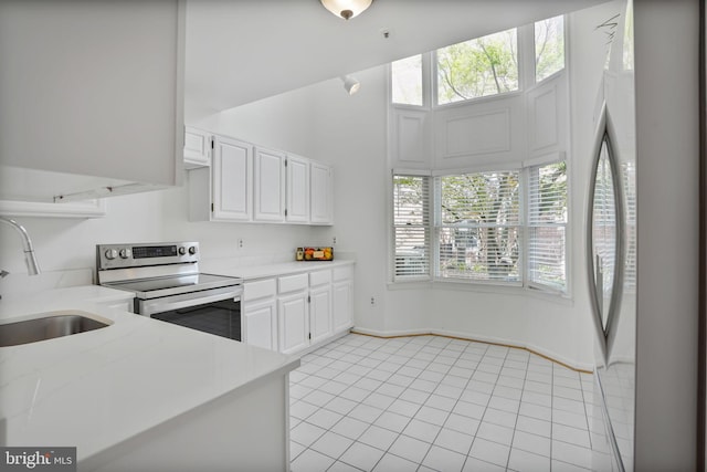 4223 N Carlin Springs Rd, Arlington, VA 22203 - kitchen with stainless steel electric stove, white cabinetry, freestanding refrigerator, and light tile patterned floors