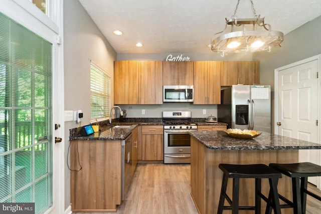 330 Timberbrook Ct, Odenton, MD 21113 - kitchen featuring appliances with stainless steel finishes, light wood-style flooring, a center island, a breakfast bar, and dark stone countertops