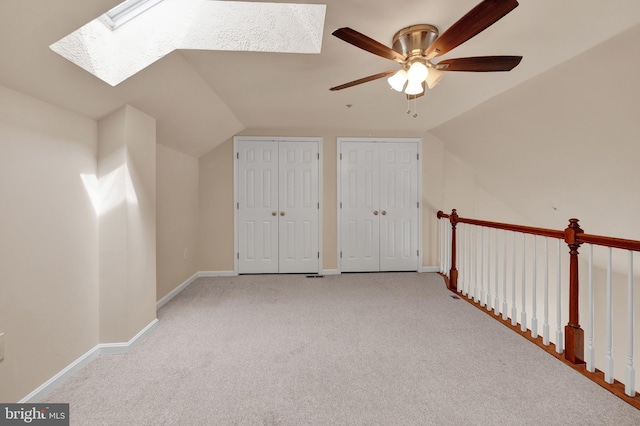 additional living space featuring baseboards, ceiling fan, carpet floors, and vaulted ceiling with skylight