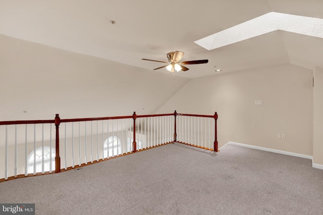additional living space featuring carpet floors, ceiling fan, baseboards, and vaulted ceiling with skylight
