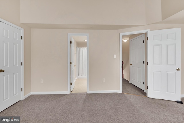 unfurnished bedroom featuring ensuite bath, carpet floors, and baseboards