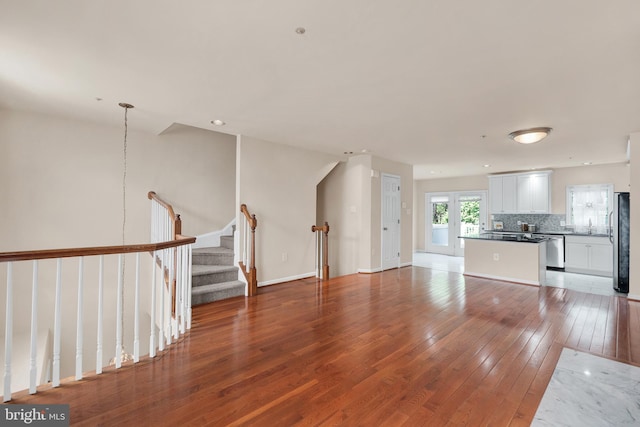 unfurnished living room with a sink, light wood-style floors, baseboards, recessed lighting, and stairs