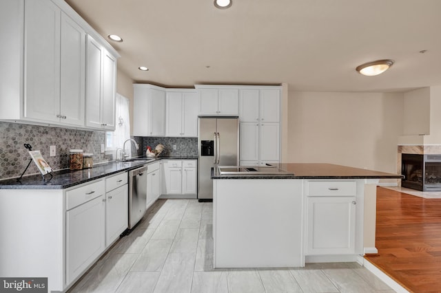kitchen with recessed lighting, a sink, stainless steel appliances, backsplash, and white cabinets