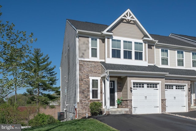 view of front of property with a garage, aphalt driveway, central air condition unit, and stone siding