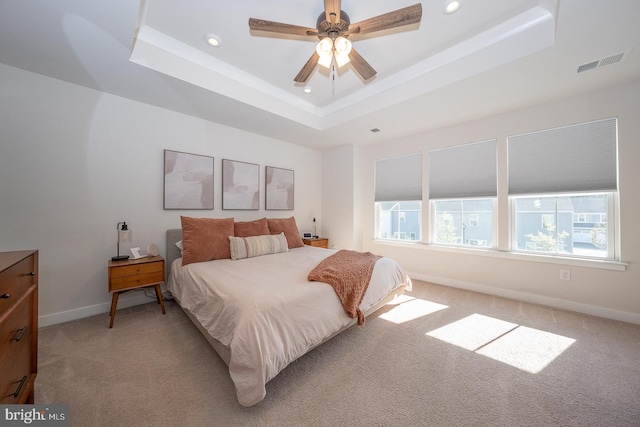 bedroom featuring recessed lighting, a tray ceiling, visible vents, and light carpet