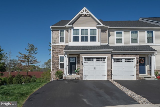 view of front of property with fence, an attached garage, driveway, and stone siding