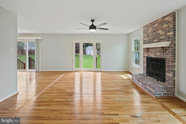 unfurnished living room featuring plenty of natural light, a fireplace, light wood-type flooring, and ceiling fan