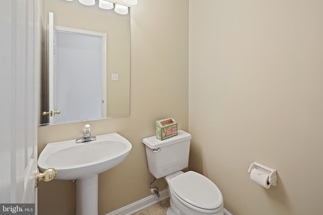 half bathroom with baseboards and toilet