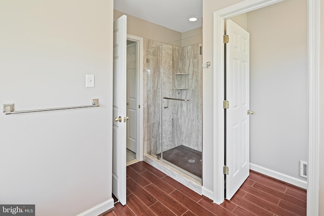 full bathroom featuring baseboards, a shower stall, wood finish floors, and visible vents
