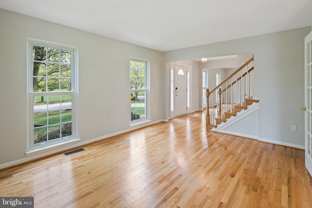 foyer featuring light wood-style floors, baseboards, and visible vents