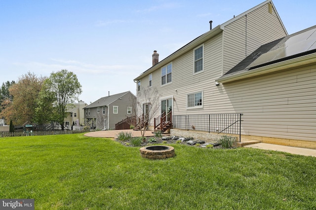 rear view of house featuring a chimney, a lawn, a residential view, fence, and an outdoor fire pit