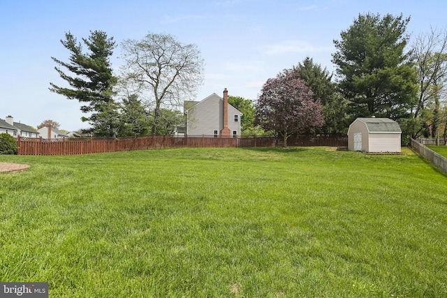 view of yard with an outbuilding, a fenced backyard, and a storage unit