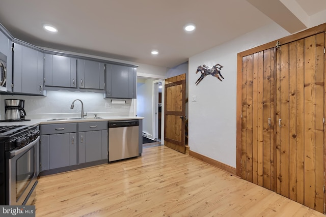 kitchen featuring light wood finished floors, a sink, stainless steel appliances, and light countertops